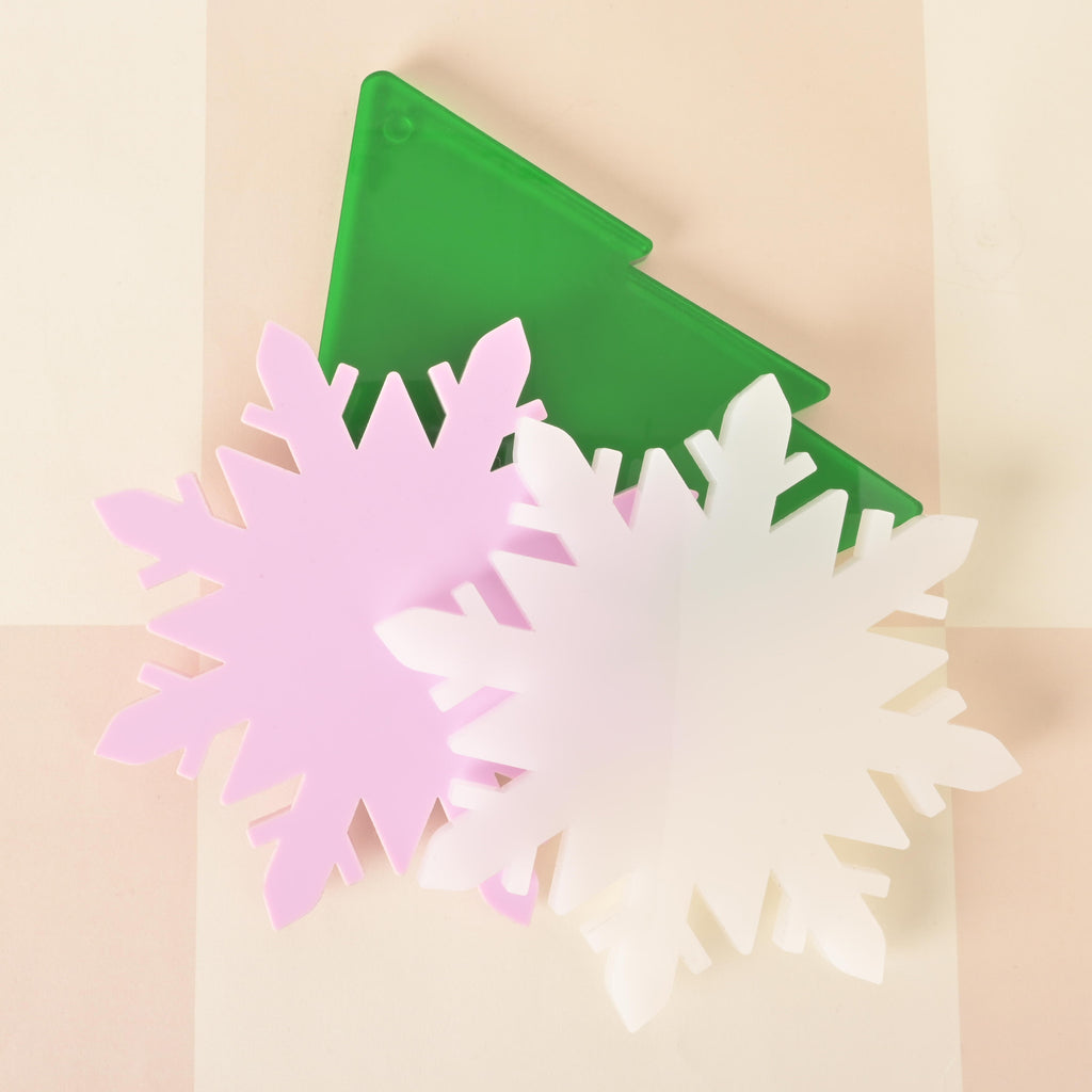 Set of acrylic holiday coasters shaped like pastel snowflakes and a green Christmas tree, festive winter table decor for parties and gifts.