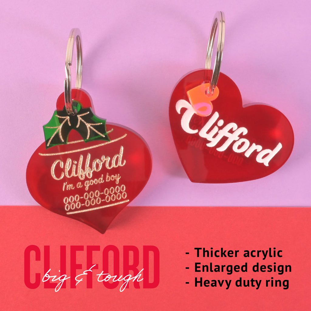 Two red heart-shaped Clifford Big & Tough pet ID tags with thicker acrylic, heavy duty ring, and engraved personalization on pink background.