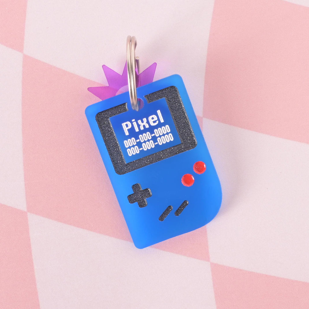 Blue retro game console pet ID tag with engraved pet name and phone number, paired with a purple star charm, fun personalized accessory for dogs and cats.