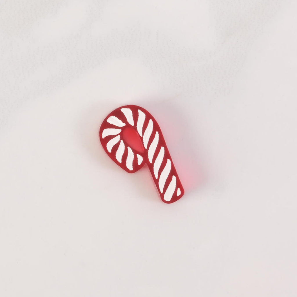 A red and white candy cane-shaped charm mini. A wooden ruler with the "EM & ME" logo is placed below the charm to show its size. The charm is shown on a solid white background.