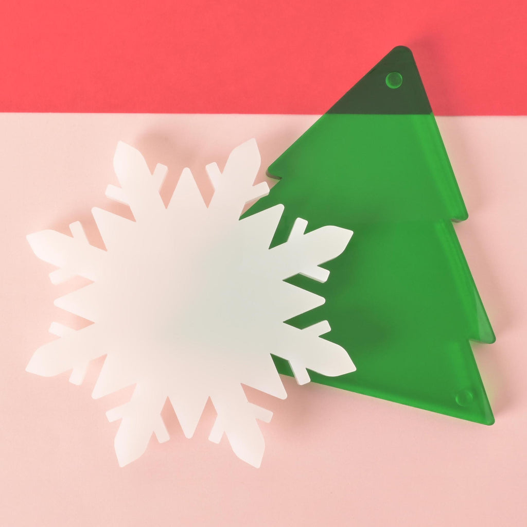 Set of acrylic holiday coasters in the shape of a green Christmas tree and a white snowflake, perfect for festive winter drinks and holiday décor. Trivet