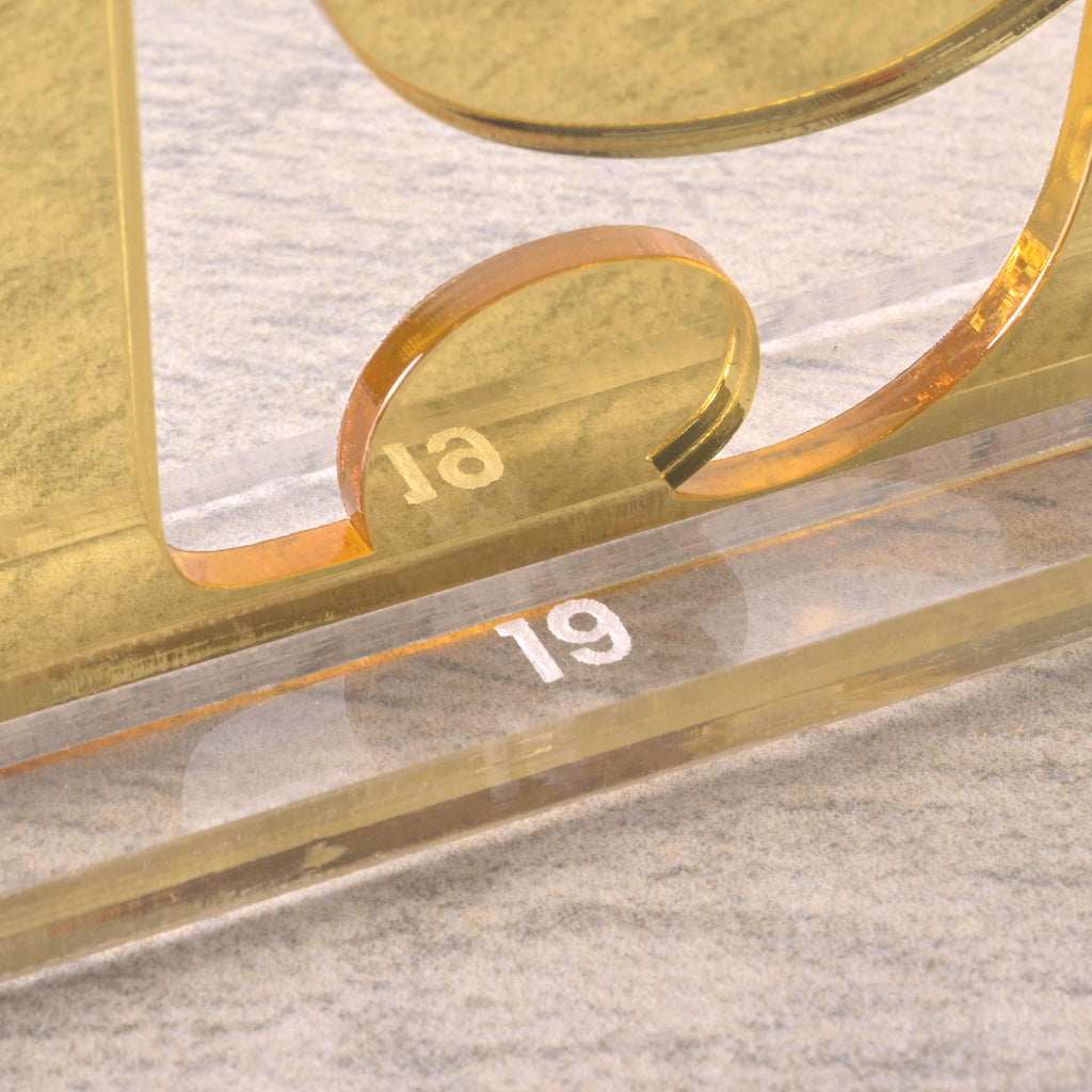 Detailed close-up of a gold acrylic table number “19” showing the engraved number on a clear acrylic base.