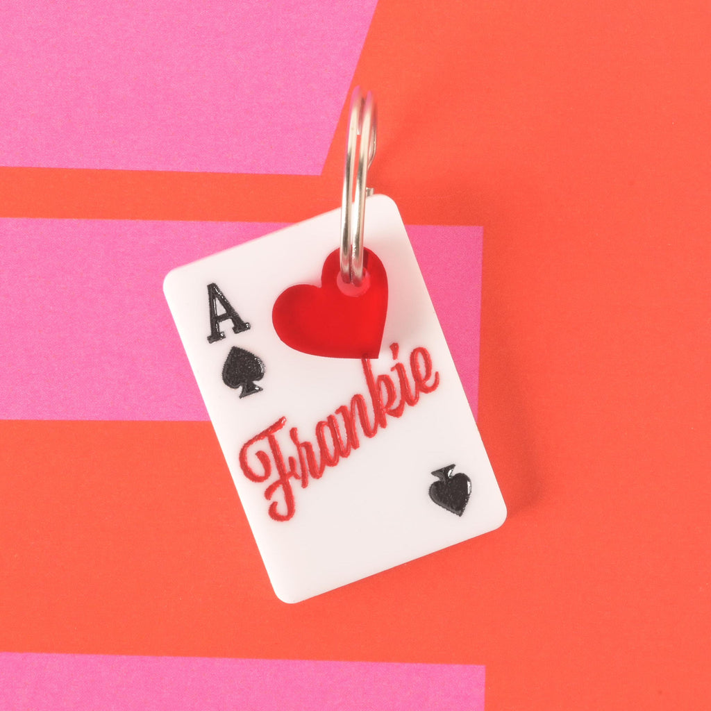 Lucky Ace playing card pet ID tag engraved with the name Frankie in red script, paired with a red heart charm on a bold red and pink background.