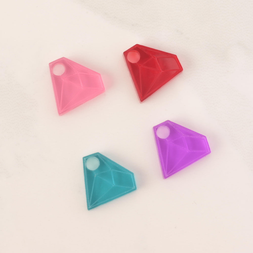 Selection of pink, red, teal and purple acrylic diamond-shaped mini charm with hole on solid white background
