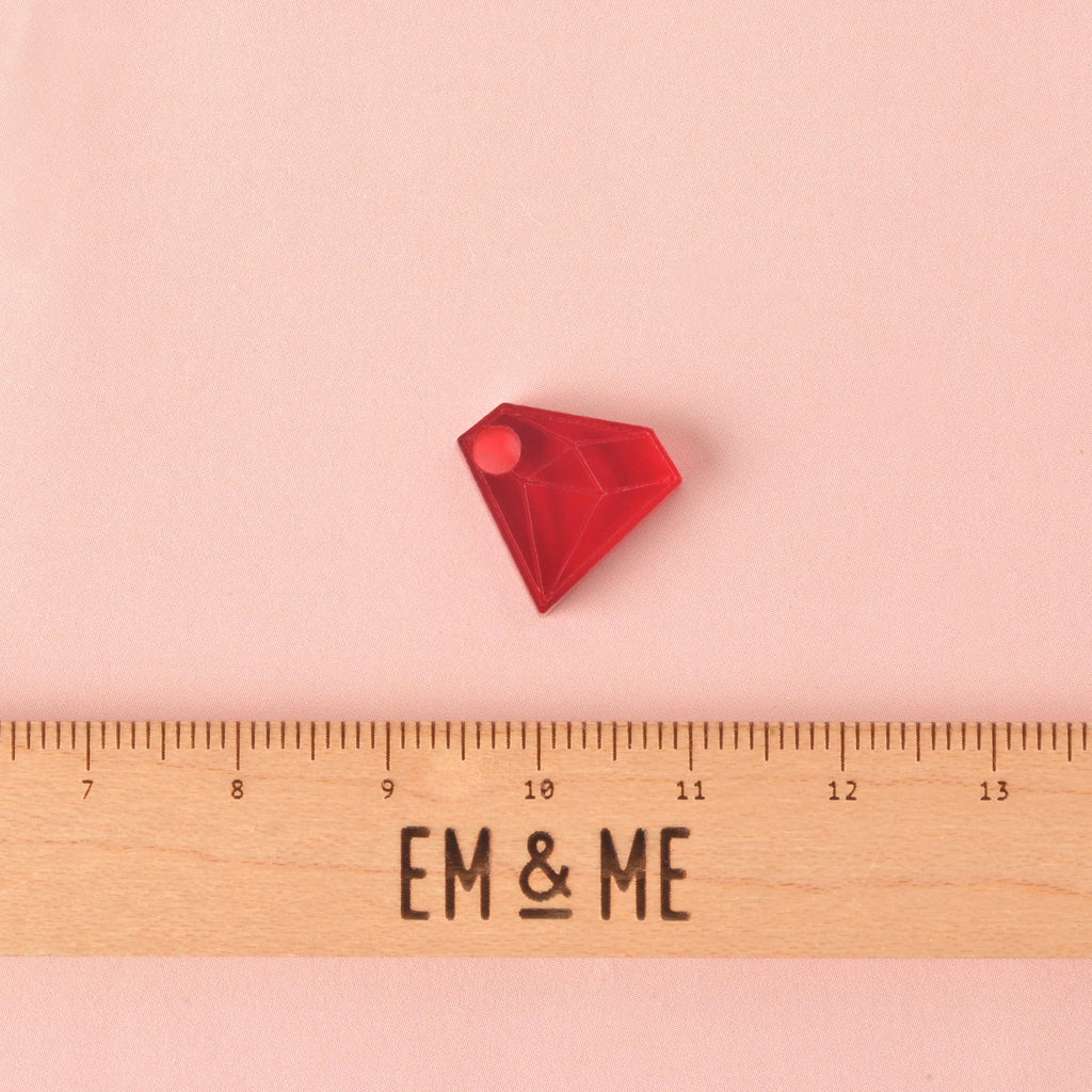 diamond-shaped mini charm with a wooden ruler that reads "EM & ME" on solid pink bacckground.