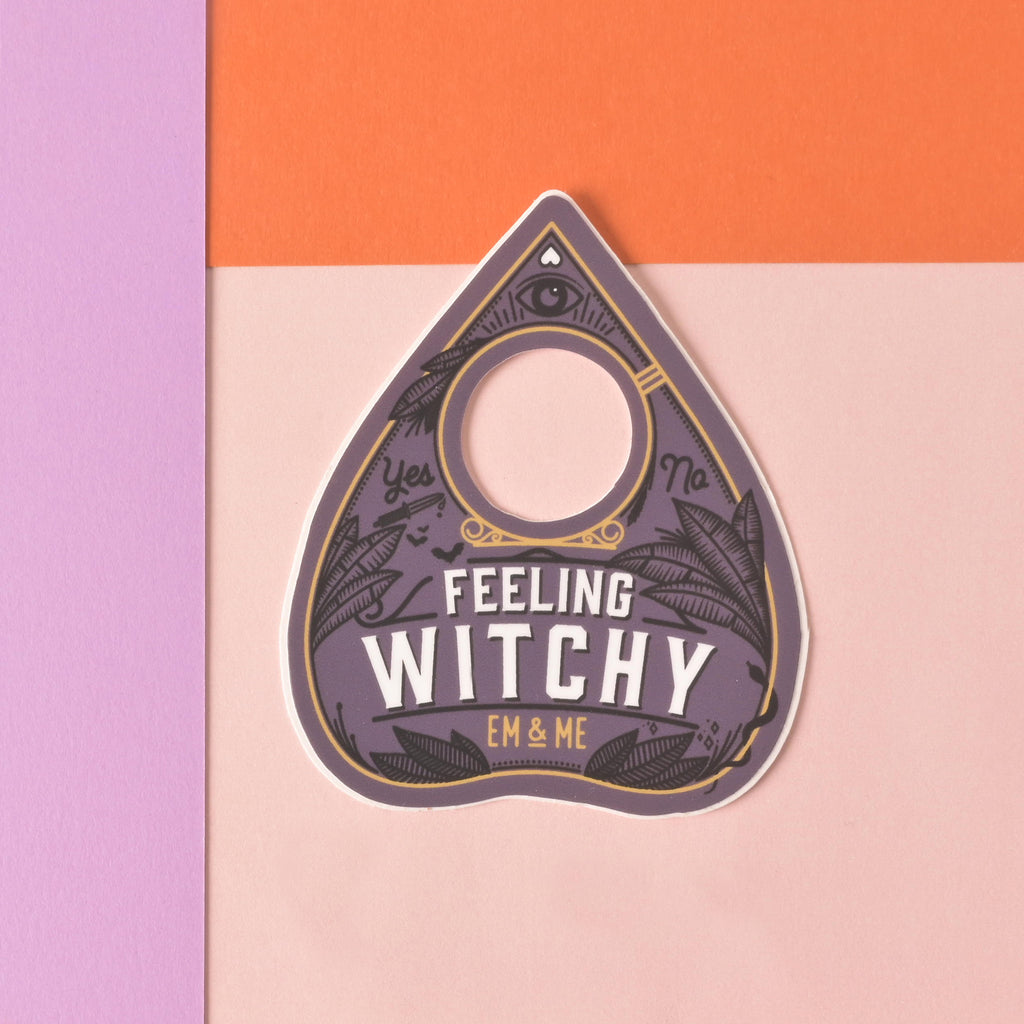 Ouija Planchet-shaped die cut sticker that reads "feeling witchy" on a color blocked background