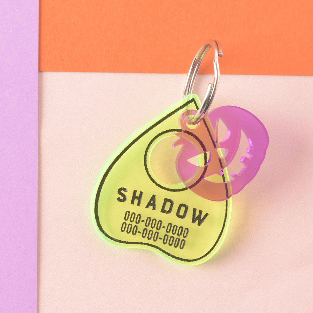 Fluorescent green ouija planchet-shaped pet ID tag with purple jack-o-lantern mini charm add on.