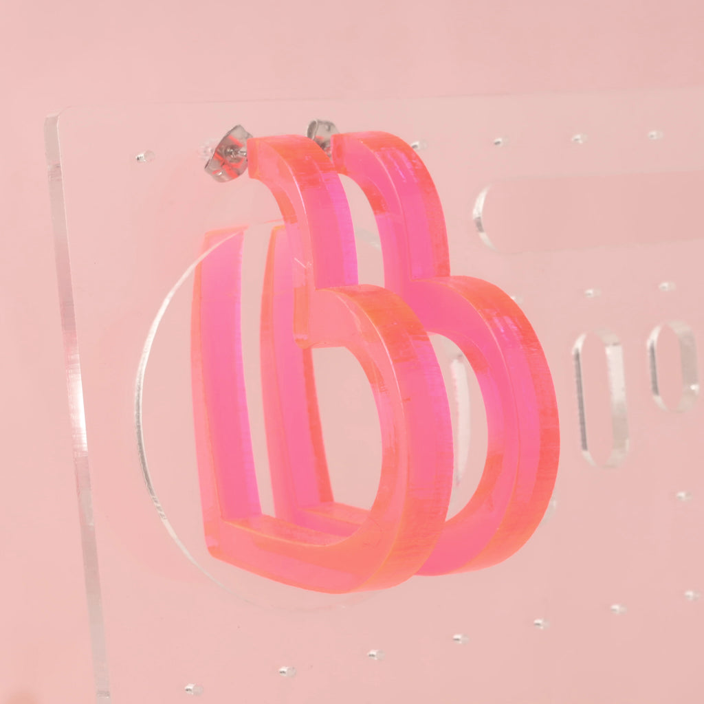 Fluorescent pink acrylic heart-shaped Hoop earrings on clear acrylic stand
