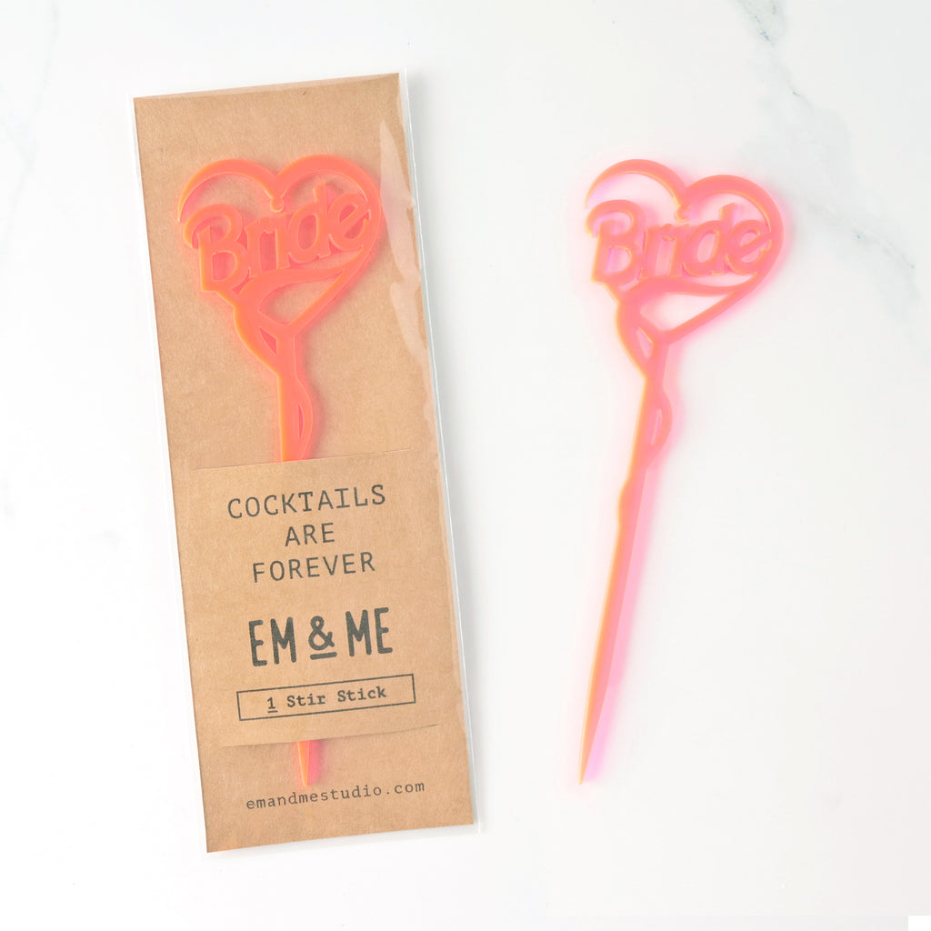 Single Barbie inspired fluorescent pink Bride cocktail stirrer packaged on brown kraft paper on marble background