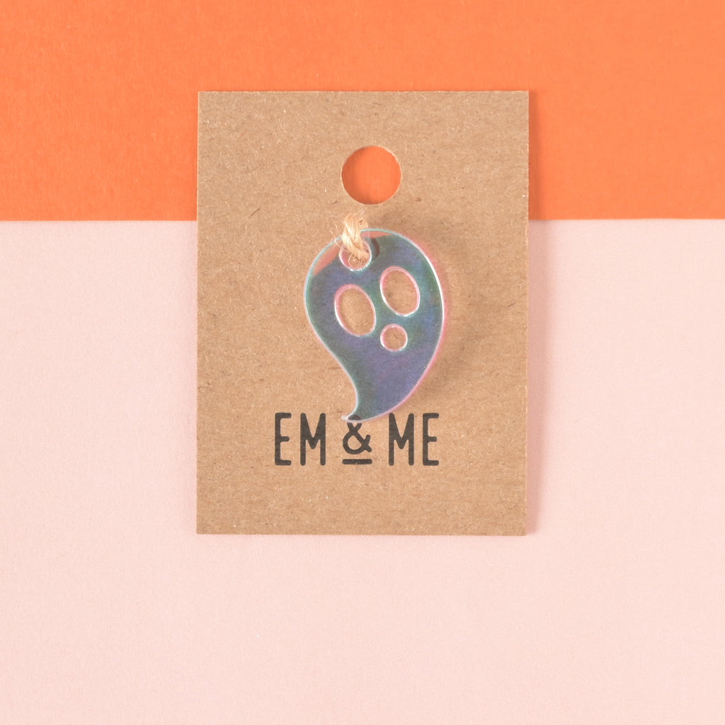 Iridescent ghost-shaped seasonal mini charm for pet tags packaged on brown kraft paper on color blocked background