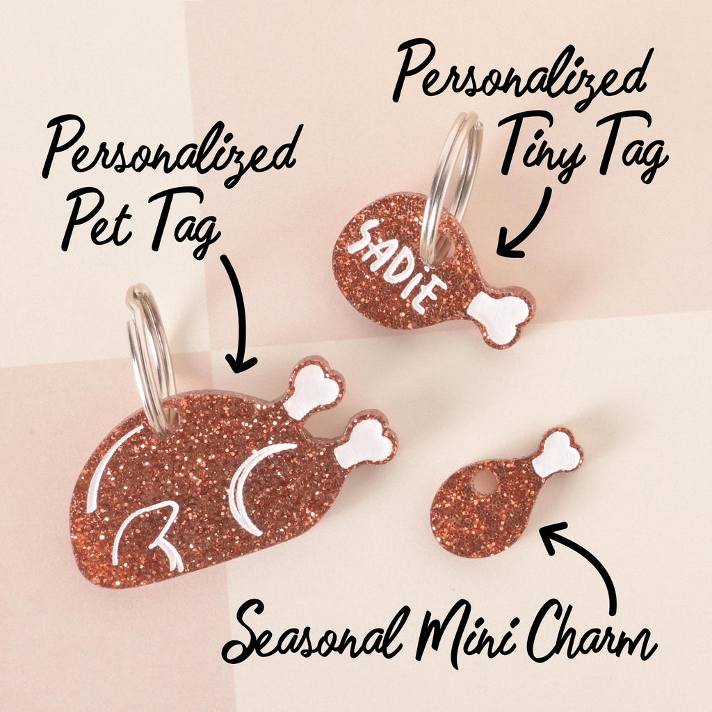Set of glittery drumstick-shaped pet ID tags including a large personalized tag, a smaller custom name tag, and a seasonal mini charm, all with white bone accents.