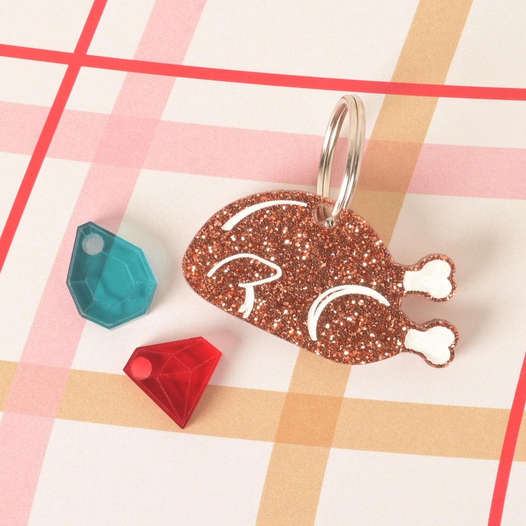 Sparkly glitter acrylic turkey-shaped pet ID tag with engraved details, shown with teal and red gem mini charms, customizable with pet name and phone number for dogs and cats.