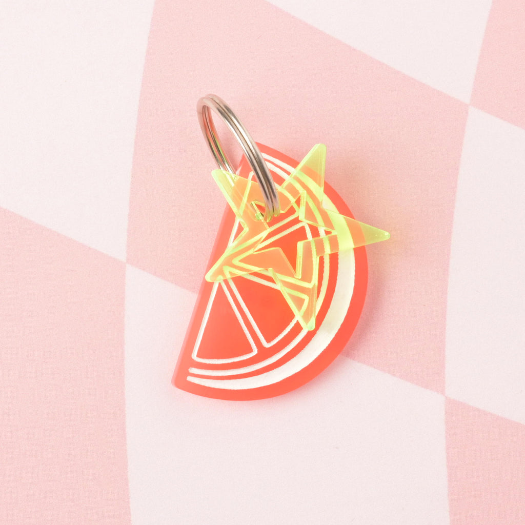 Grapefruit colored fruit wedge personalized pet ID tag with fluorescent green star mini charm  on checked pink background