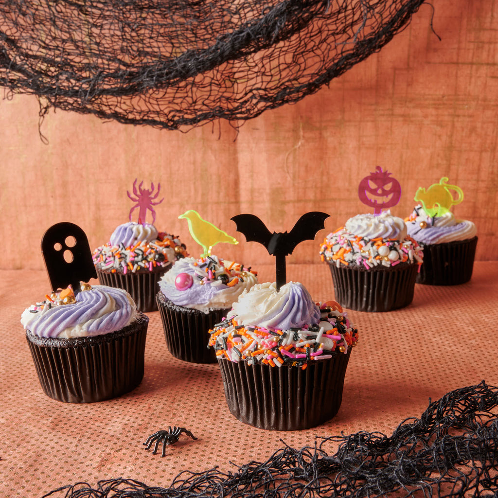 collection of 6 short cocktail, decorative sticks for drinks or desserts in halloween themed cupcakes on orange background with black spider webs 