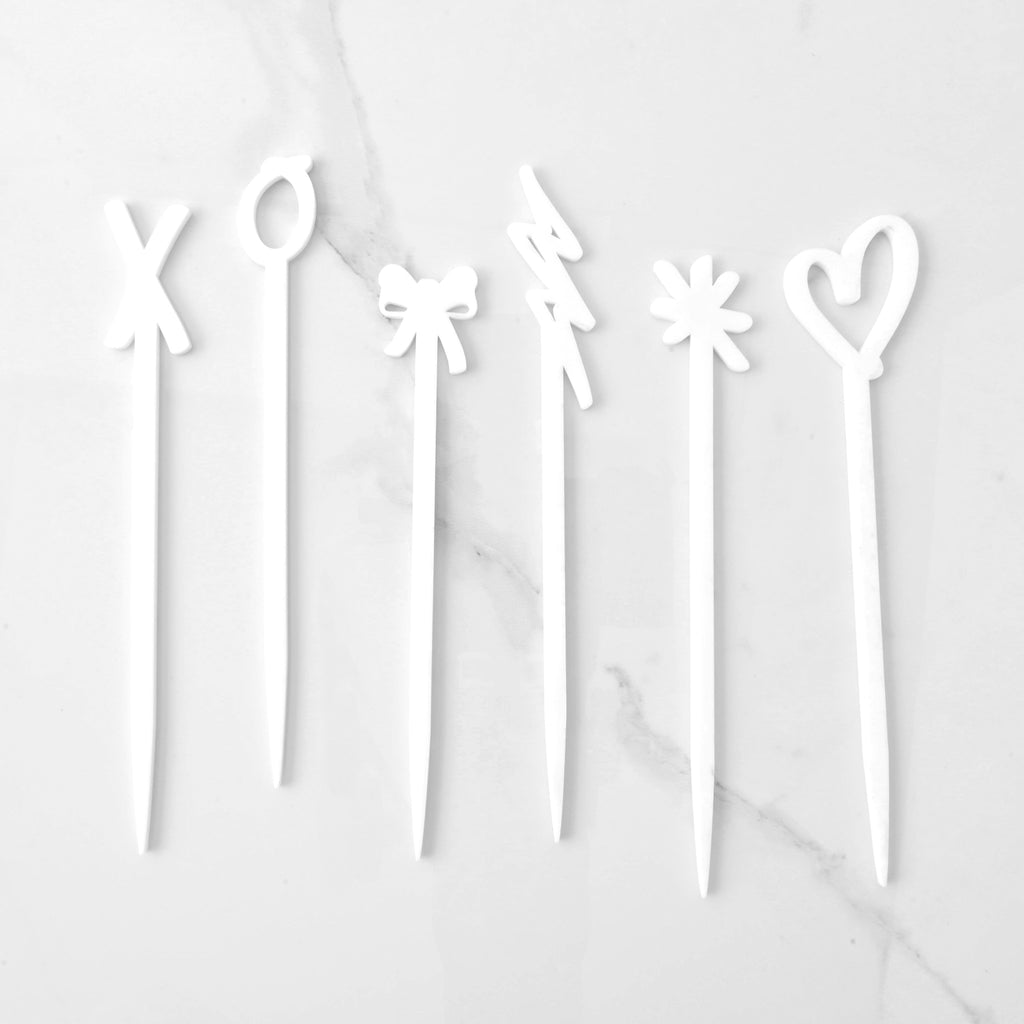 set of six opaque white hand drawn love cocktail stir sticks. Hugs, kisses, bow, heart, asterisk and lighting bolt shapes on solid white background