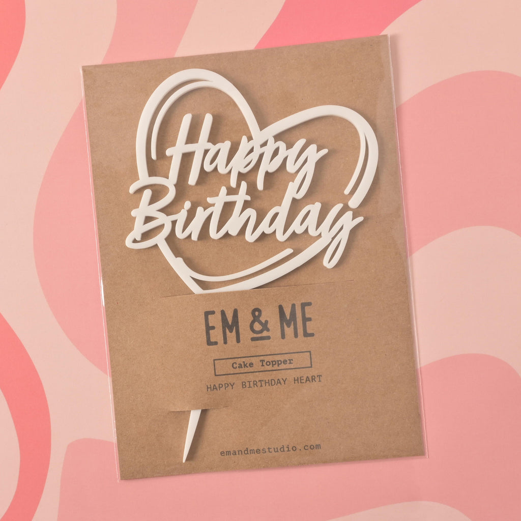 
Based on the image you've uploaded, here are the SEO values for the title and alt text.

SEO Title
"Happy Birthday" Cake Topper in Packaging 🎁🎂

This title is concise and accurately describes the main subjects in the image. It uses relevant keywords like "Happy Birthday," "cake topper," and "packaging" to improve search visibility.

Alt Text
A white cake topper that says "Happy Birthday" inside a heart outline, sealed in its retail packaging. The brown cardstock packaging has "EM & ME" printed on it. The