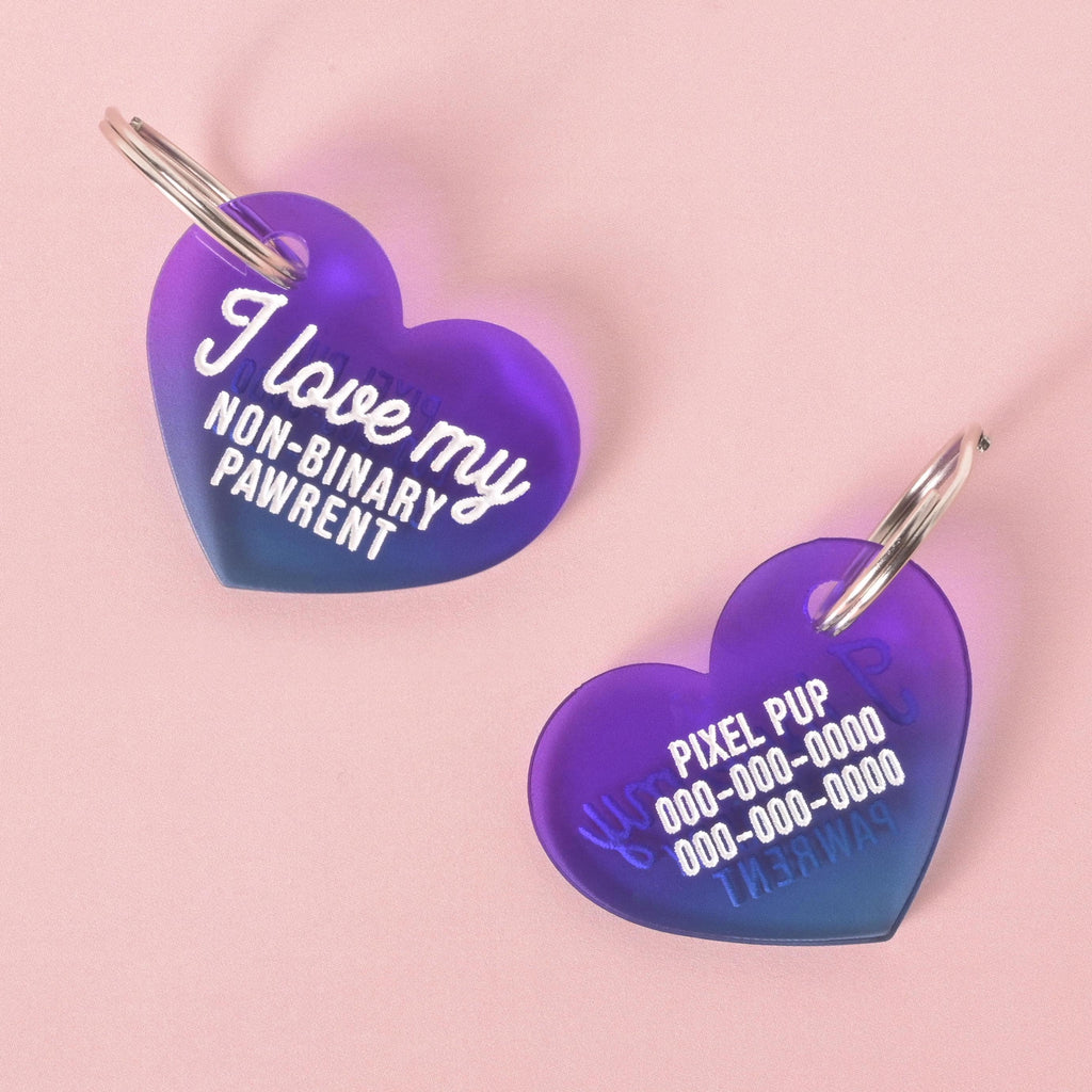 Purple heart-shaped pet ID tags shown front and back. One side reads “I love my non-binary pawrent” in white script, and the reverse side displays customizable pet name and phone numbers. LGBTQ+ pride dog and cat accessory.