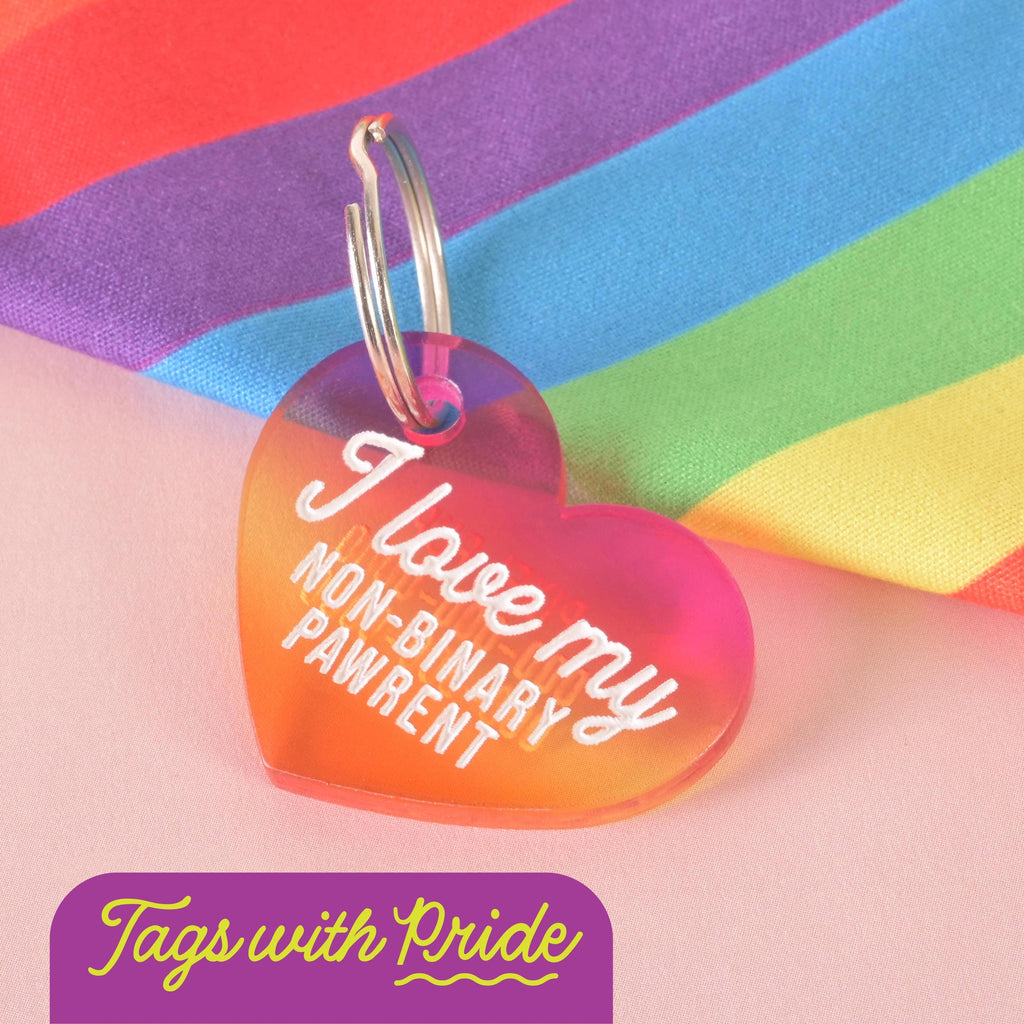 Heart-shaped pet ID tag in pink and orange gradient engraved with “I love my non-binary pawrent,” displayed against a rainbow pride flag. LGBTQ+ inclusive dog and cat accessory celebrating pet parents.