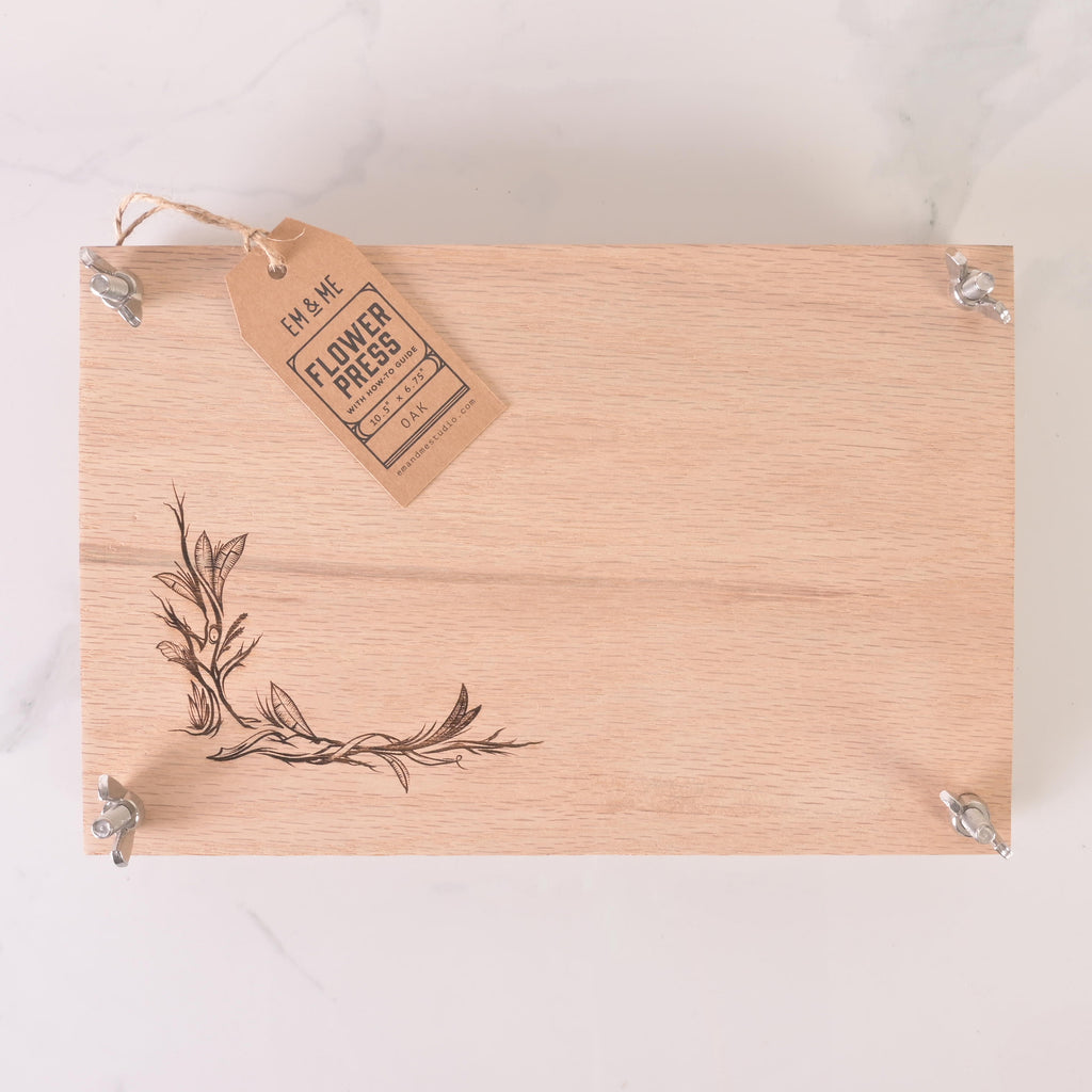 Rectangular wooden flower press with engraved floral design, metal bolts, and kraft label tag for DIY flower preservation and crafts.