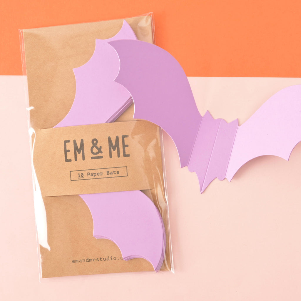set of 10 Lavender paper die cut bats. Halloween decor in brown kraft paper packaging on color blocked background.