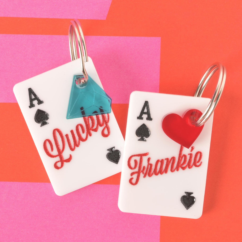 Pair of Lucky Ace pet ID tags, one engraved with Lucky and teal gem charm, the other personalized with Frankie and red heart charm.