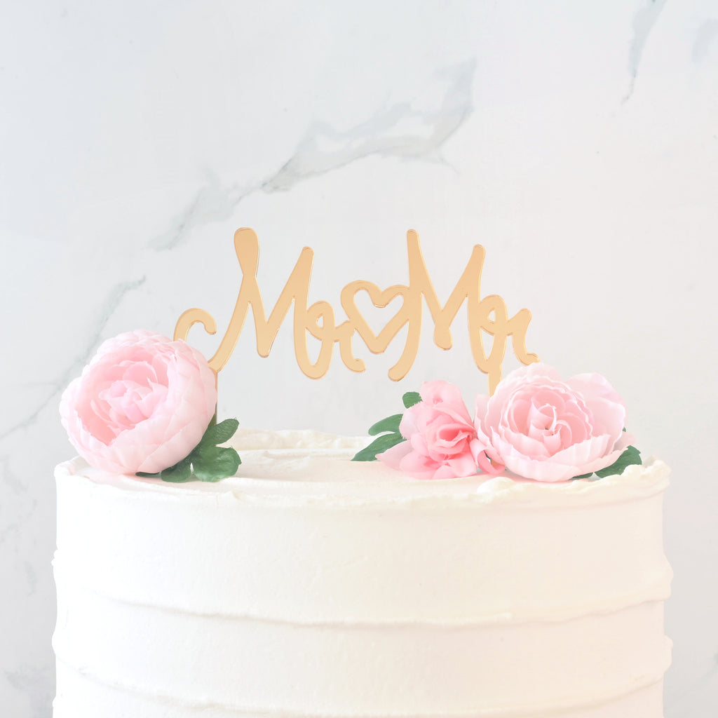mirror gold cake topper in cake that reads "MR MR" with a heart in the middle for wedding. Inclusive LGBTQIA+ celebration.