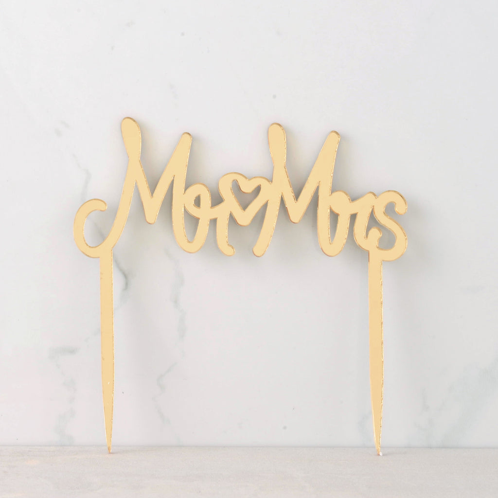 Mirror gold cake topper that reads "Mr Mrs" with a heart in the middle for wedding cake.