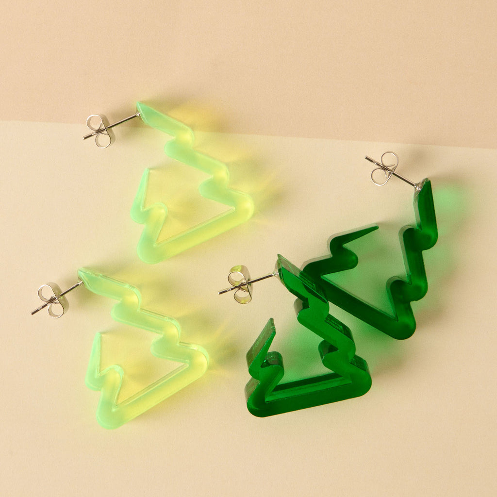 A comparison of two pairs of earrings shaped like Christmas trees or zig-zag hoops: one pair in fluorescent neon yellow-green acrylic and the other in dark translucent emerald green acrylic. These are lightweight, festive statement earrings.