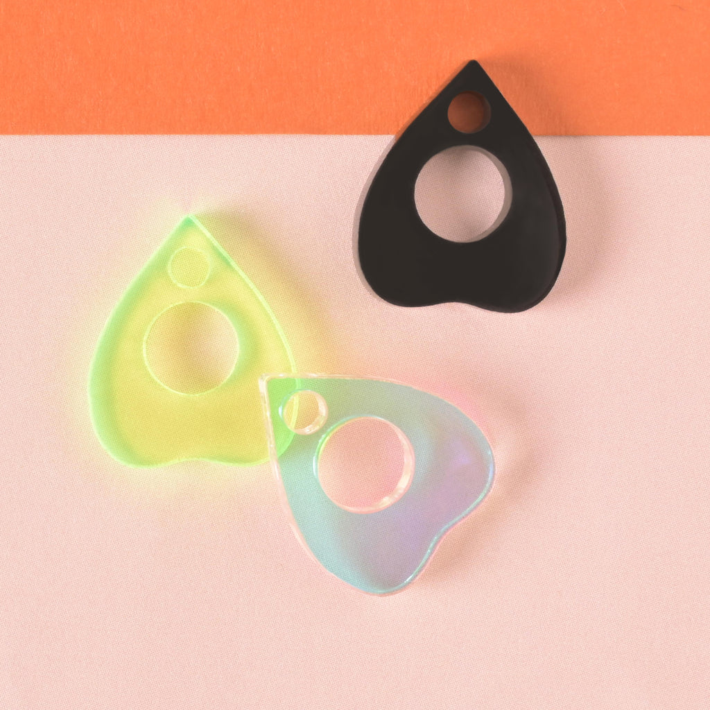collection of three ouija planchet-shaped mini add on charms for pet tags in fluorescent green, iridescent and opaque black on color blocked background