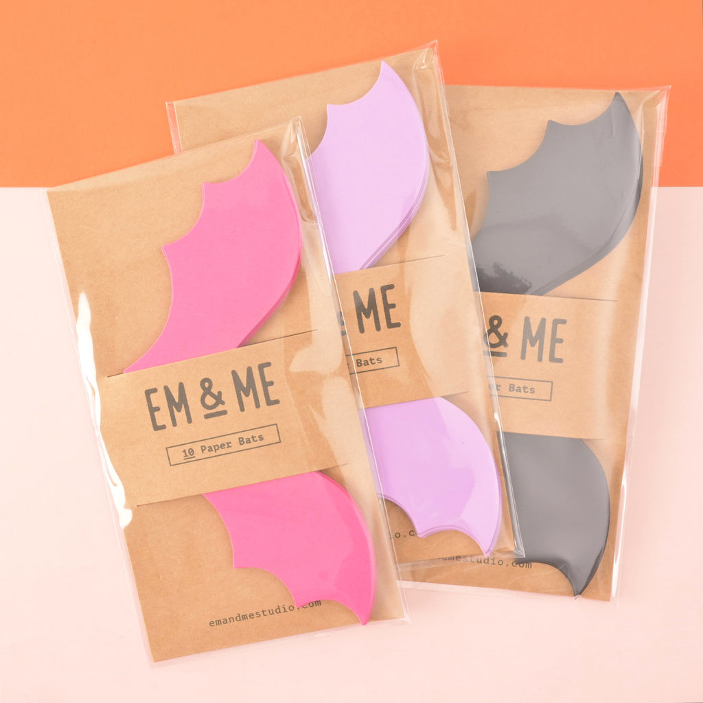 Collection of Packaged paper bats in three different colors. Pink, Lavender and black bas packaged in brown kraft paper 