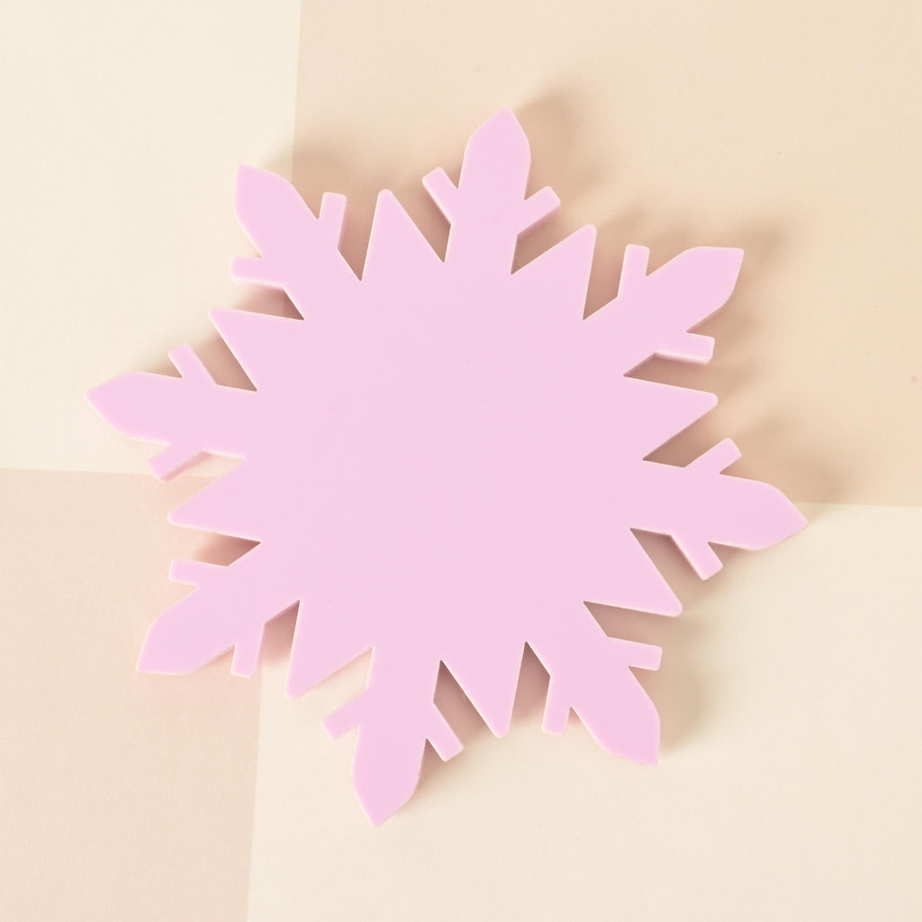 Pastel pink acrylic snowflake coaster displayed on a neutral checkered background, a festive winter accent for home and holiday decor.