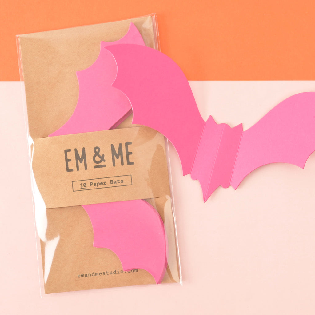 set of 10 pink paper die cut bats. Halloween decor in brown kraft paper packaging on color blocked background.