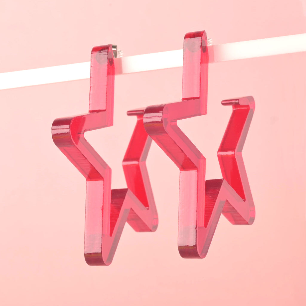 Red Acrylic Star-shaped Hoop earring hanging in front of solid pink background