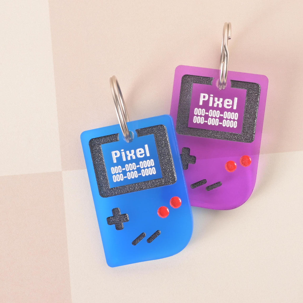 Set of retro game console pet ID tags in blue and purple with custom engraved name and phone number, geeky gamer pet tags for dogs and cats.