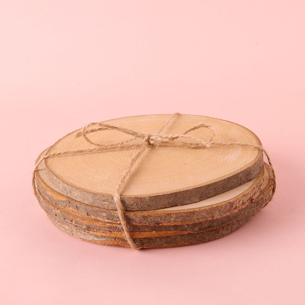 A stack of several circular, natural wood slices with visible bark edges, securely tied together with jute twine. The set of unfinished wood discs is perfect for rustic coasters or craft projects.