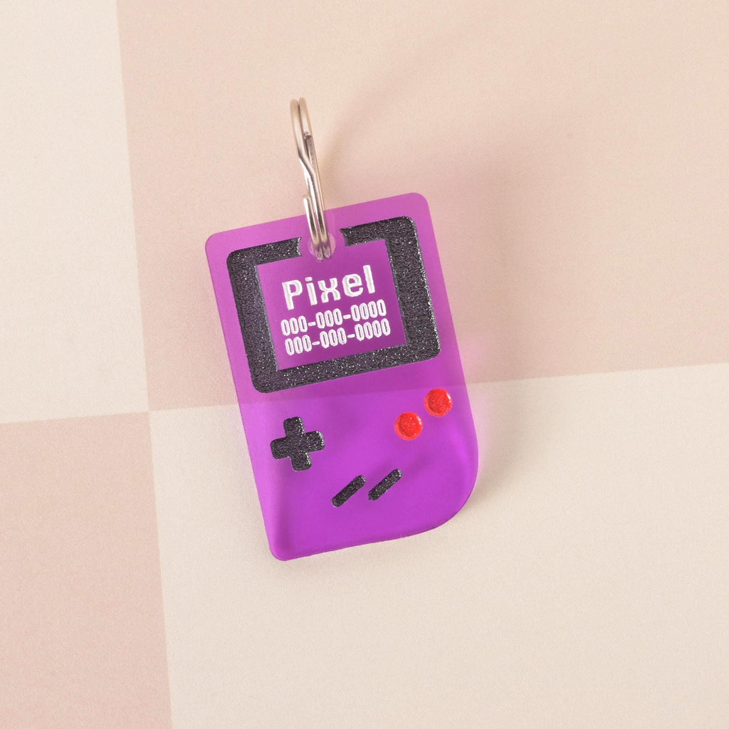 Small purple retro game console pet ID tag with engraved name and phone number, shown with ruler for scale, fun tiny tag for cats and small dogs.