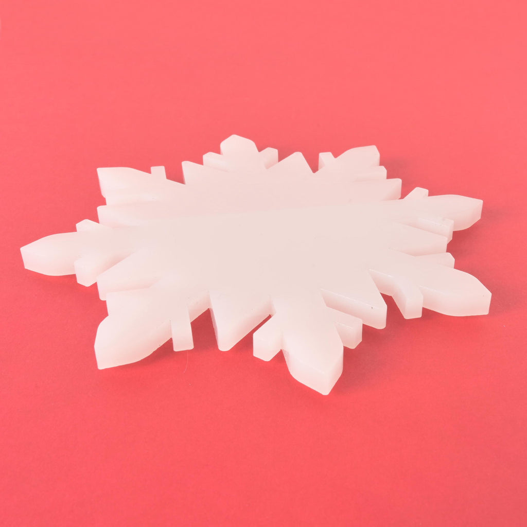 White snowflake-shaped coaster on a red background, festive winter decor