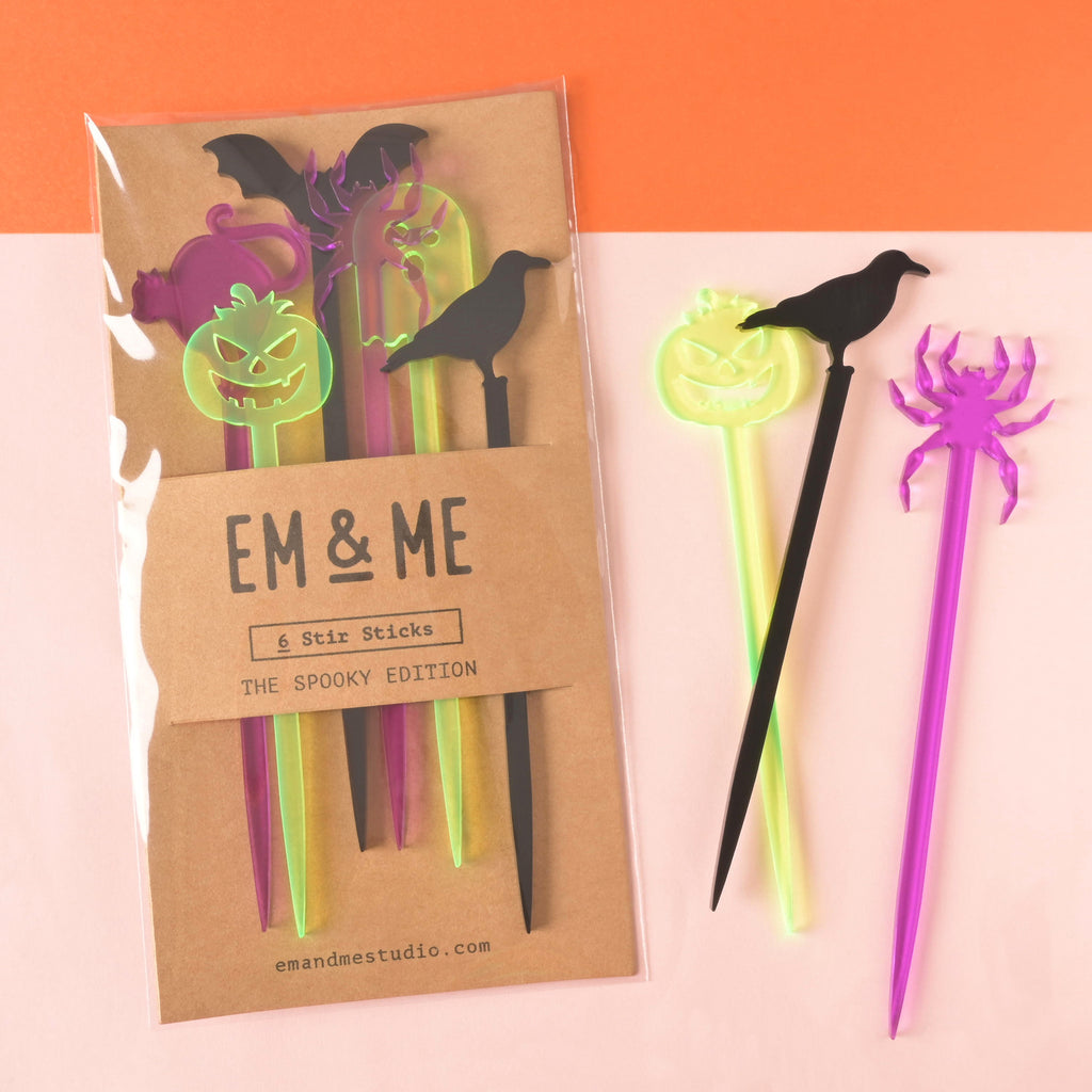 Package of six different halloween shaped cocktail stir sticks with fluorescent green jack-o-lantern, black crown and purple spider to the side.