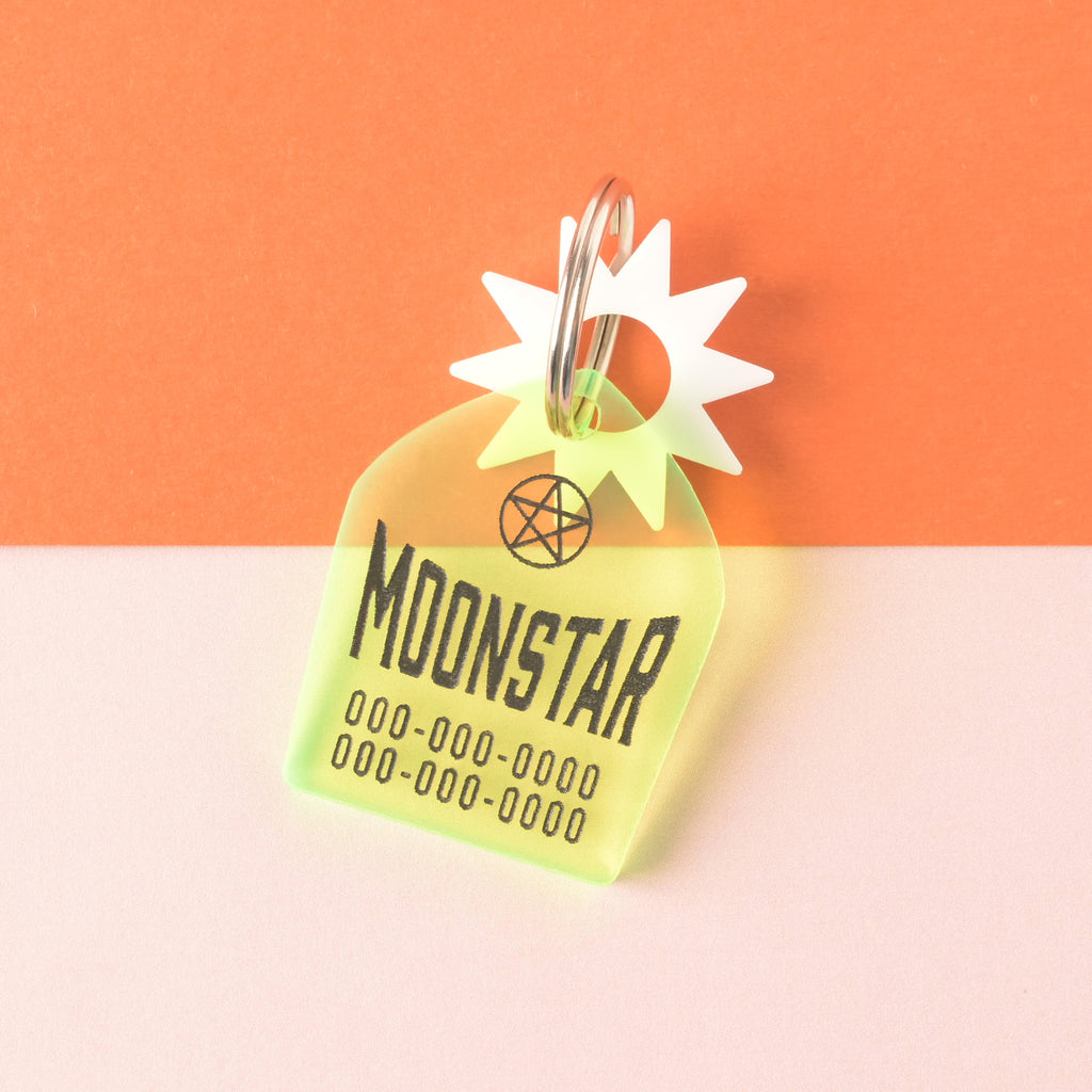 Fluorescent green gravestone-shaped pet tag with white sun mini and black place holder text for pet name and phone numbers on color blocked background