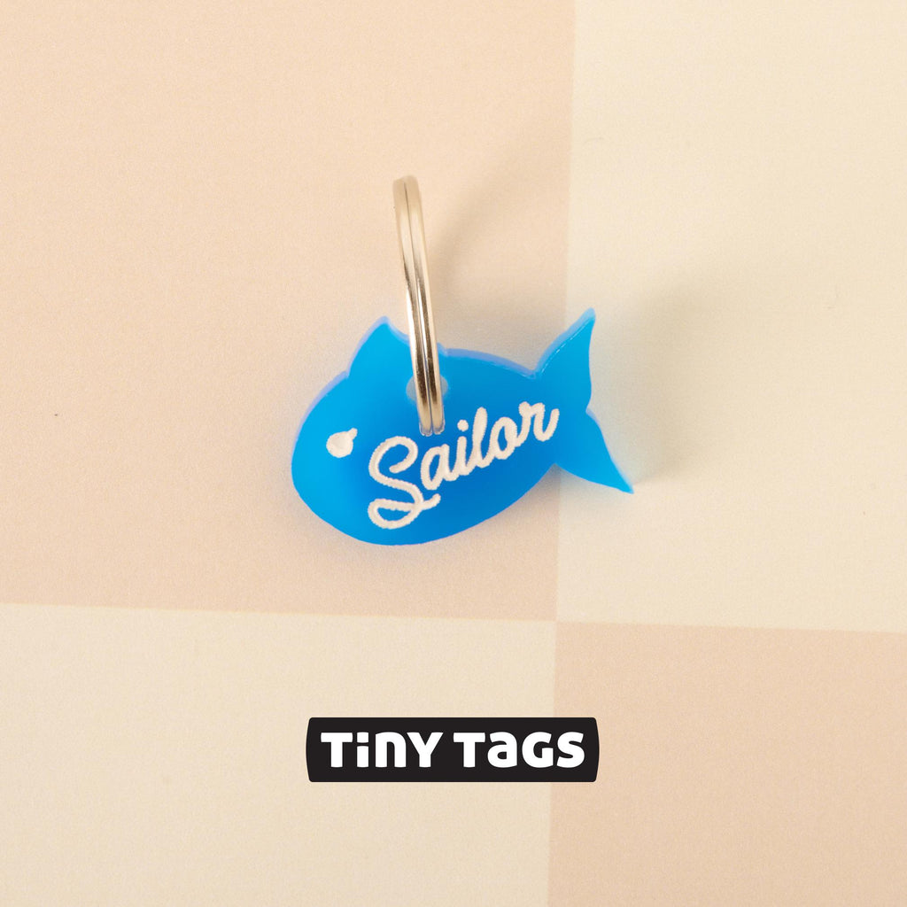 Tiny Tags blue fish-shaped pet ID tag with “Sailor” name engraving, lightweight personalized charm for small dogs and cats.