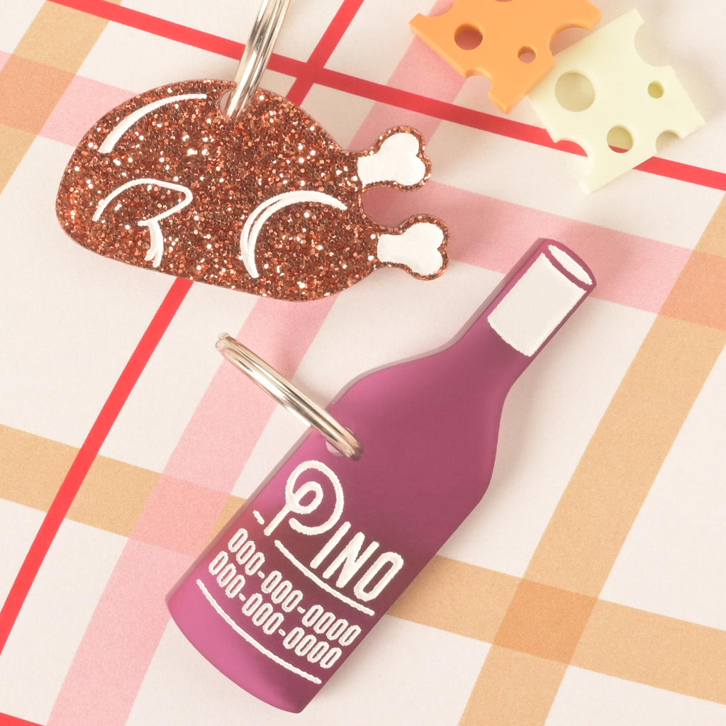 Glittery turkey leg pet ID tag and purple wine bottle pet name tag with engraved phone number details, playful acrylic dog and cat accessories.