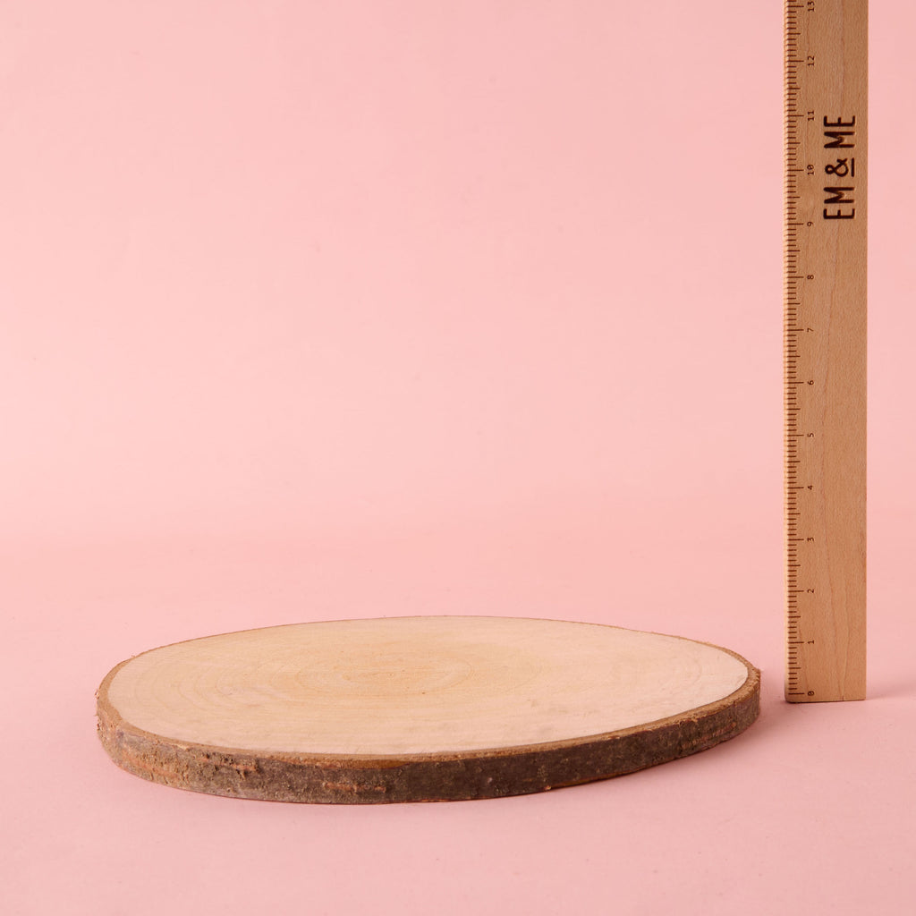 A single, large circular natural wood slice with visible growth rings and a bark edge, suitable for a centerpiece or trivet. The disc is displayed next to a wooden ruler to indicate its large size.