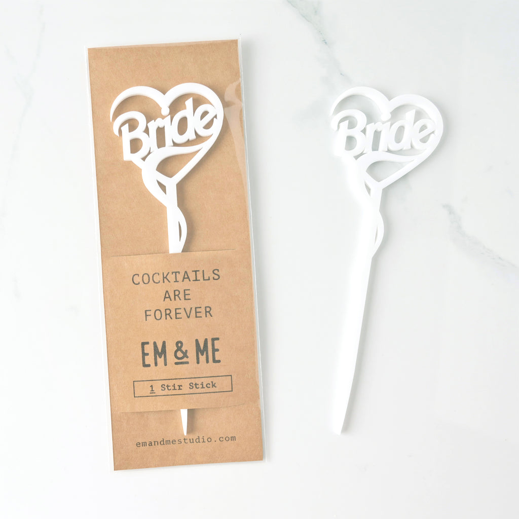 Single Barbie inspired white Bride cocktail stirrer packaged on brown kraft paper on marble background