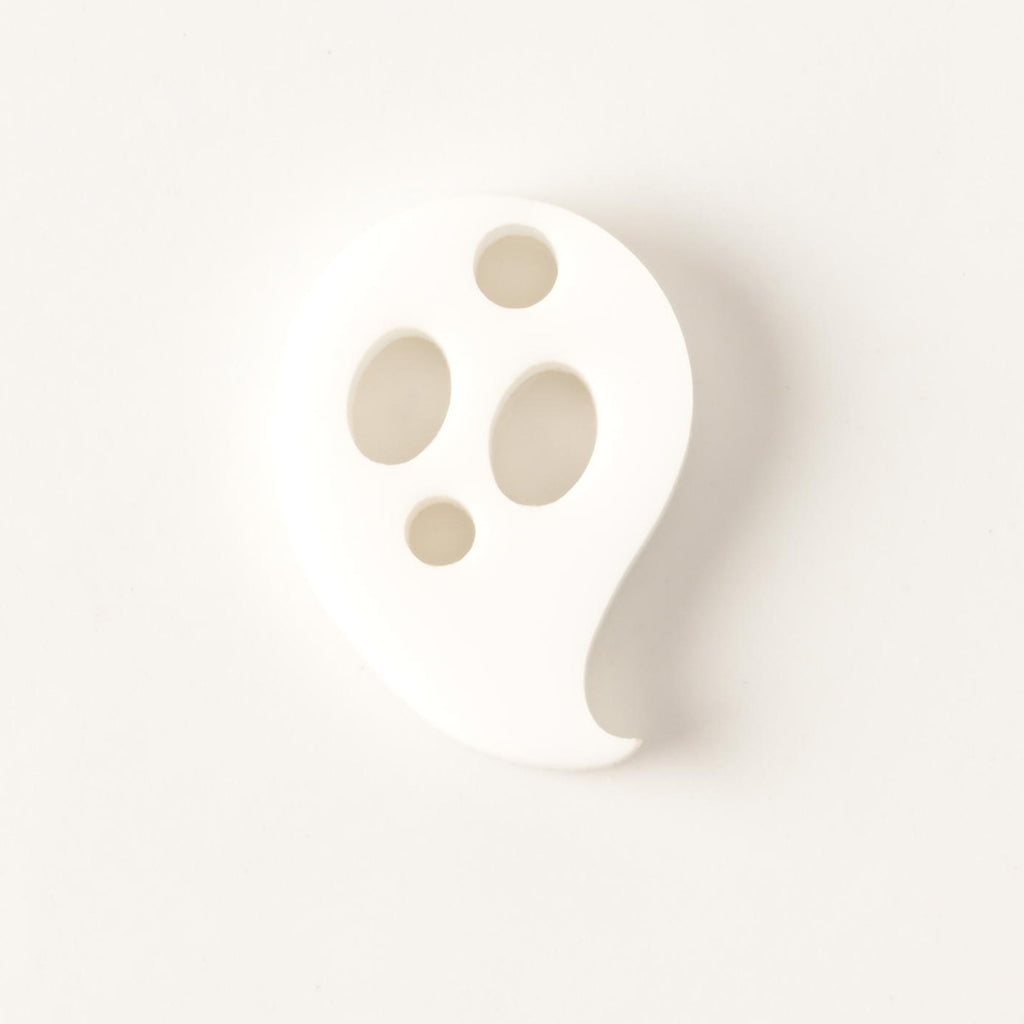 Opaque white ghost-shaped mini charm with hole for hanging on solid white background