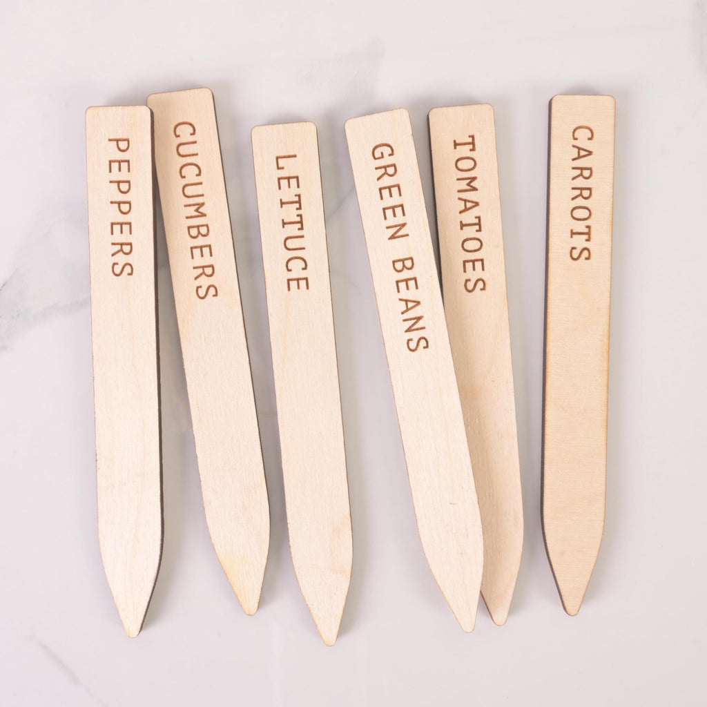Six engraved wooden vegetable plant markers labeled Peppers, Cucumbers, Lettuce, Green Beans, Tomatoes, and Carrots on a white background.