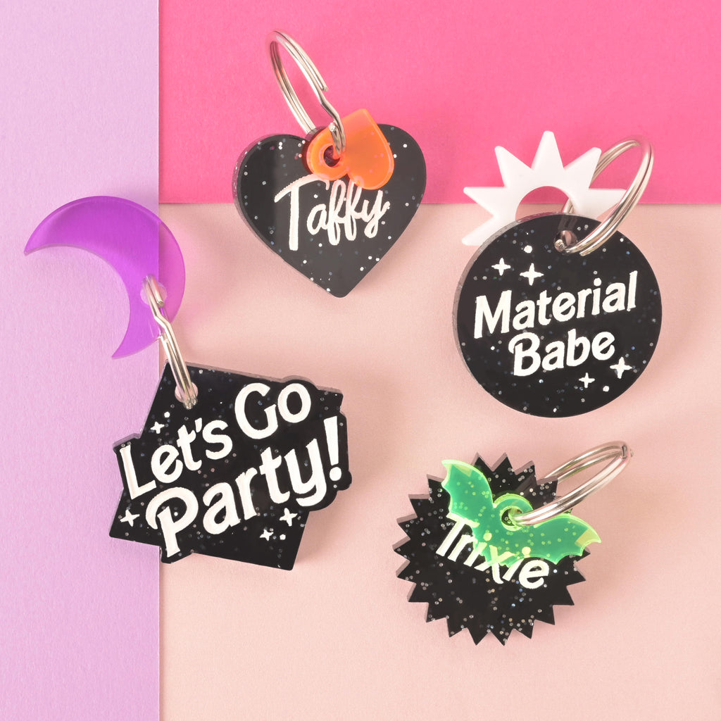 Collection of black glitter barbie themed Personalized pet tags with colorful add-on mini charms on purple, pink and peach background.