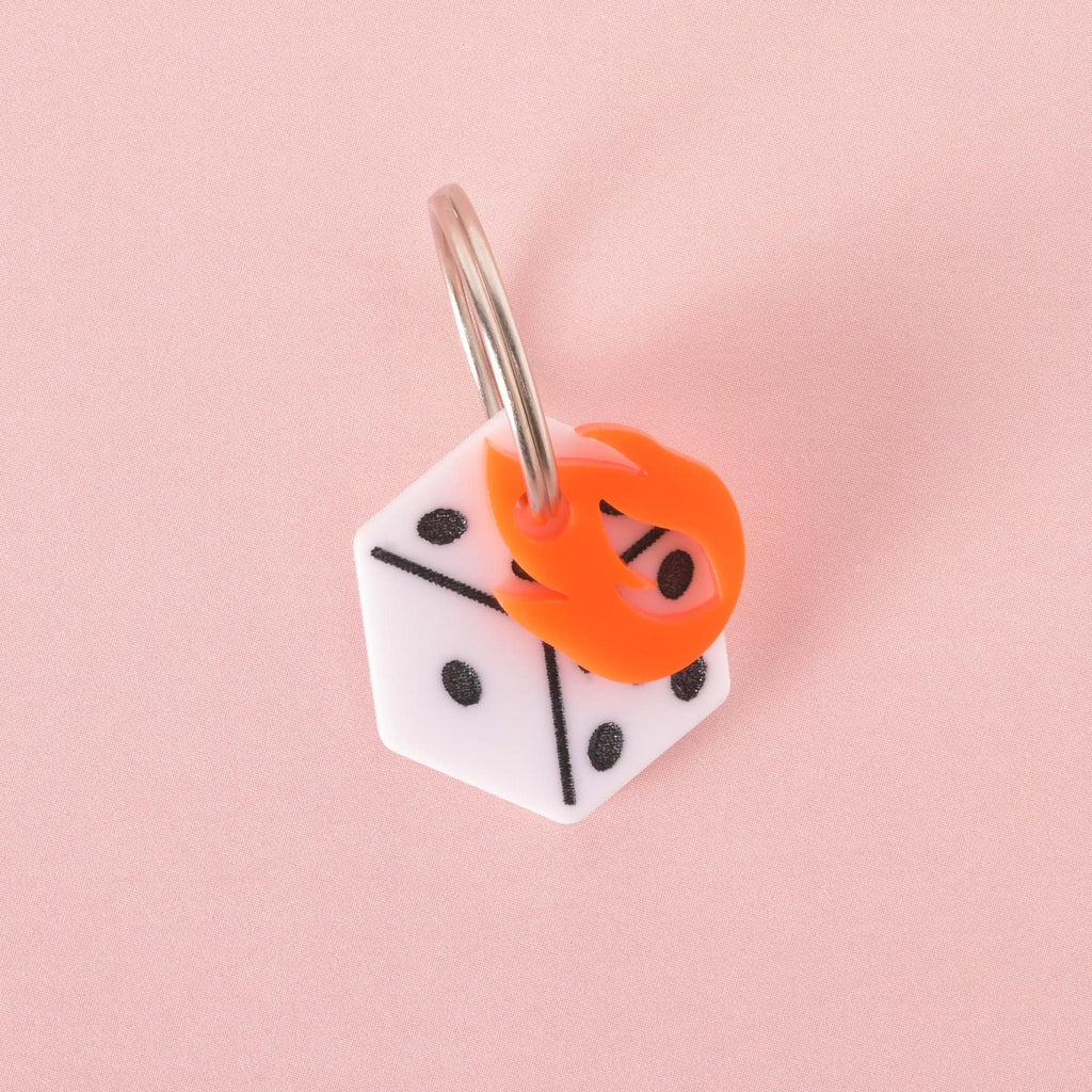 Bold dice-shaped pet ID tag with orange flame detail on a soft pink background.