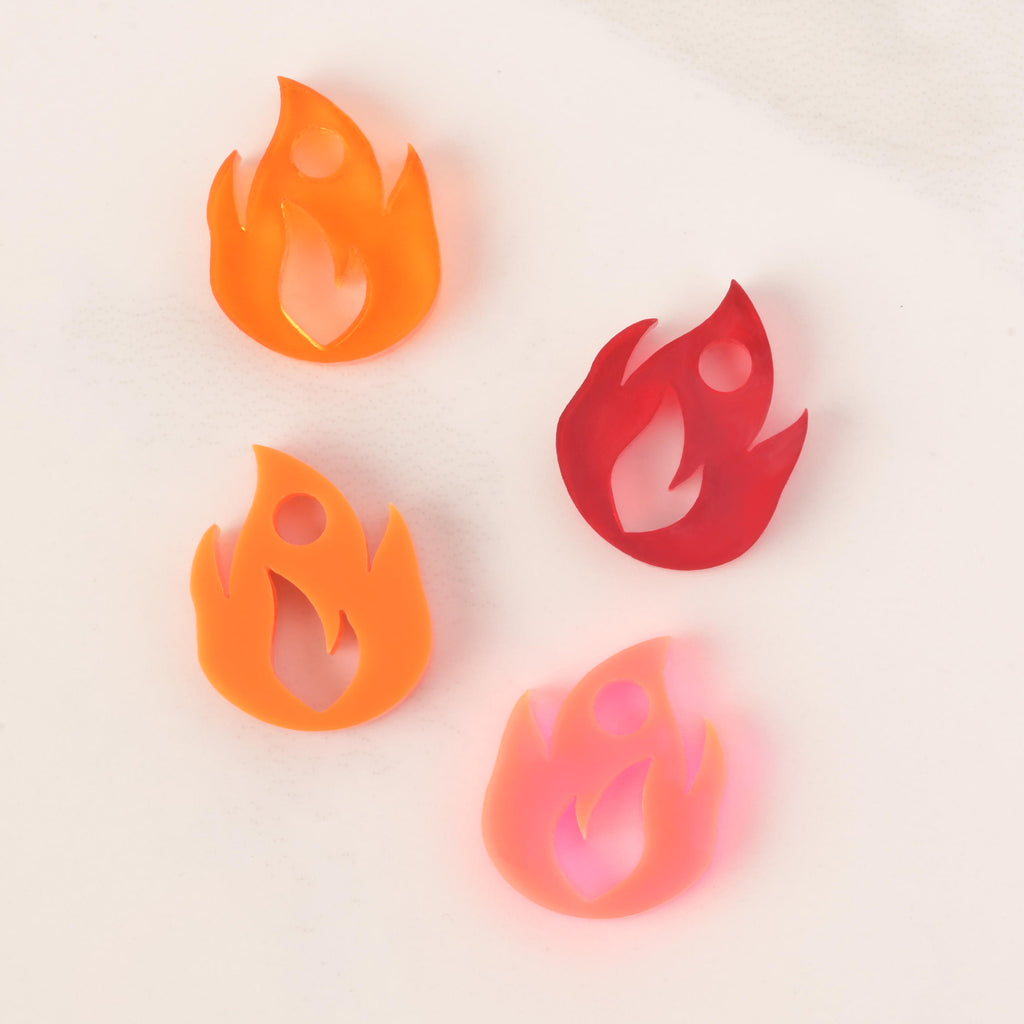 selection of four flame-shaped mini charms showing color options. opaque orange, transparent orange, red and fluorescent 