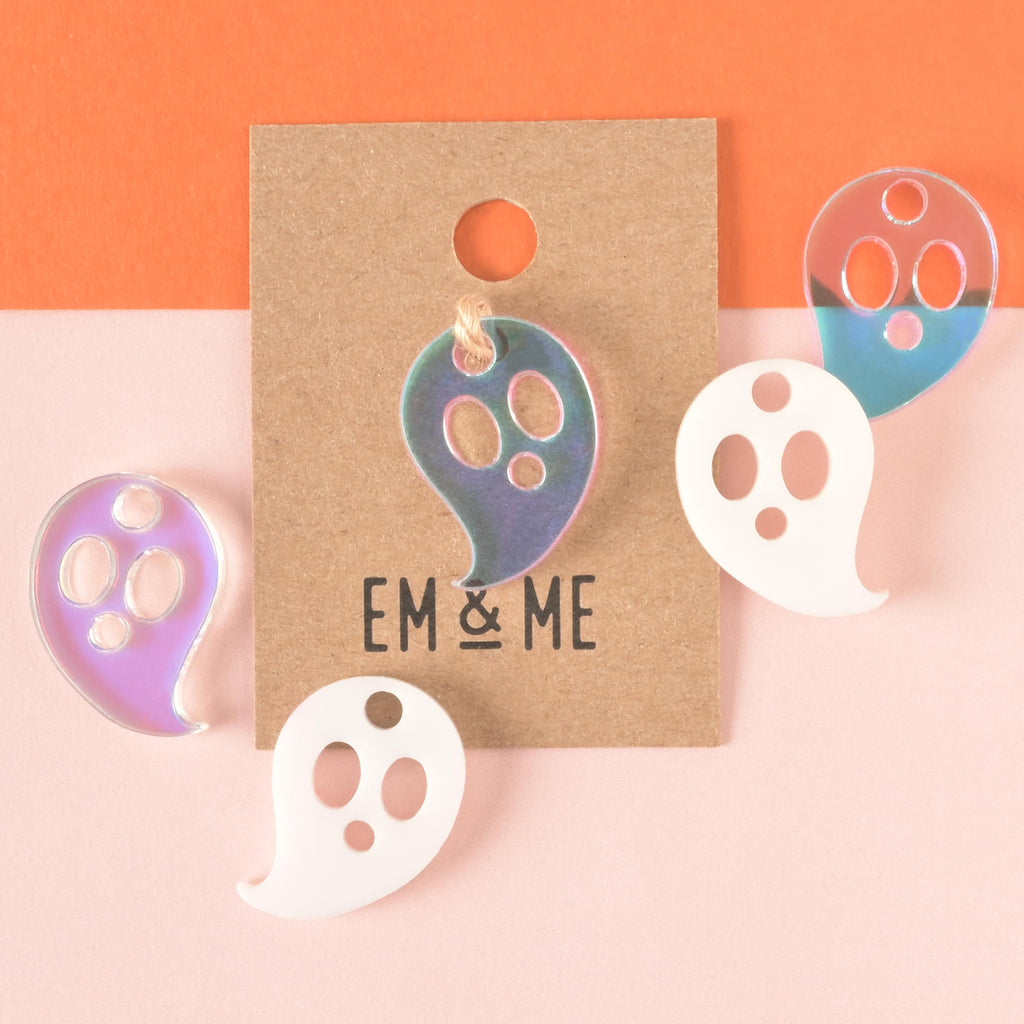 Iridescent ghost-shaped mini charm packaged on brown Kraft paper card with iridescent and white ghosts to the side on color blocked background