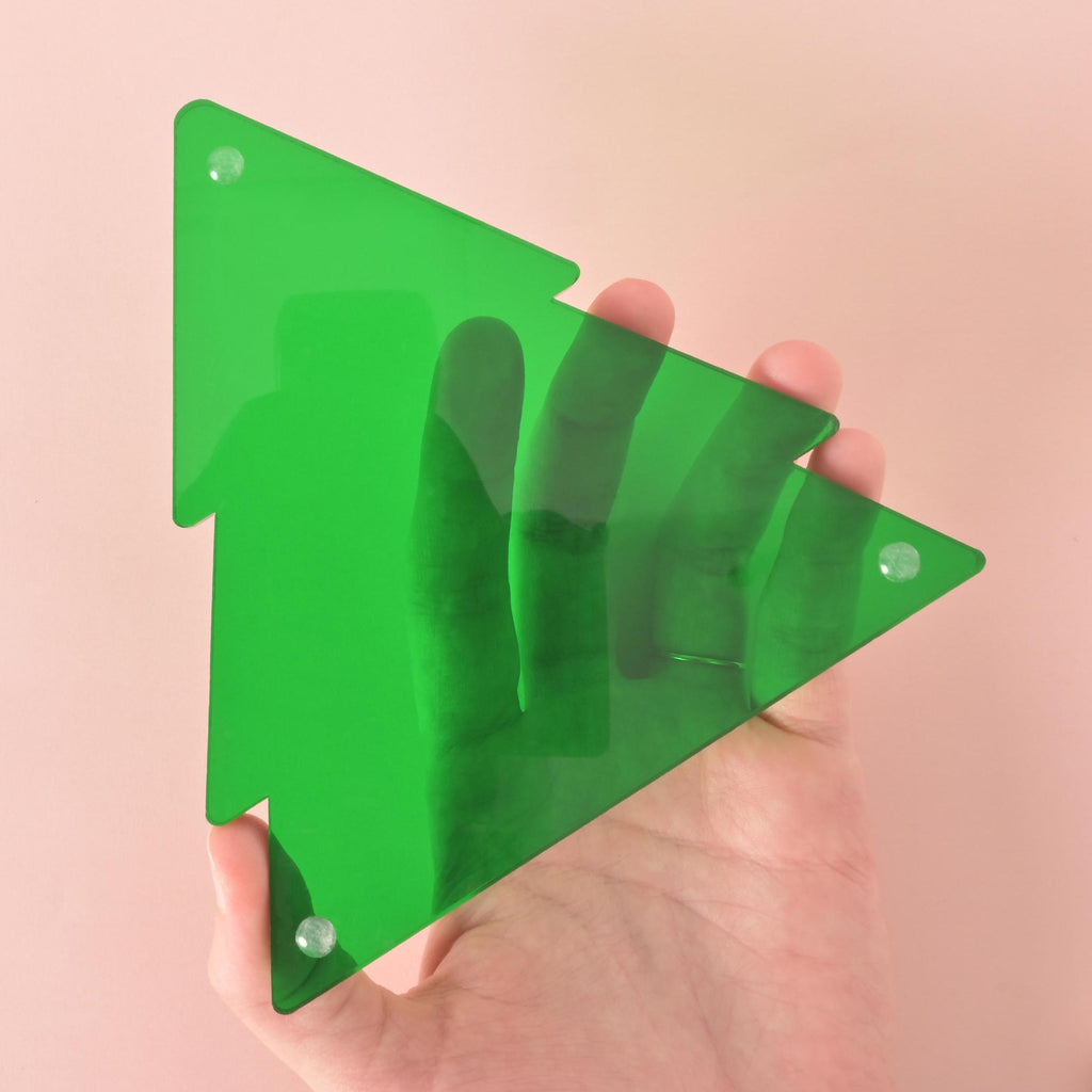 Hand holding green acrylic Christmas tree ornament – shows size and thickness of modern holiday decor piece